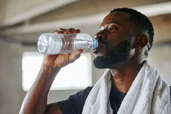 Image of man drinking water to improve hydration Loughborough after work out.
